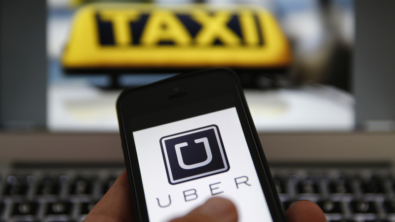 An illustration picture shows the logo of car-sharing service app Uber on a smartphone next to the picture of an official German taxi sign in Frankfurt, September 15, 2014. A Frankfurt high court will hold a hearing on a recent lawsuit brought against Uberpop by Taxi Deutschland on Tuesday.  San Francisco-based Uber, which allows users to summon taxi-like services on their smartphones, offers two main services, Uber, its classic low-cost, limousine pick-up service, and Uberpop, a newer ride-sharing service, which connects private drivers to passengers - an established practice in Germany that nonetheless operates in a legal grey area of rules governing commercial transportation. The company has faced regulatory scrutiny and court injunctions from its early days, even as it has expanded rapidly into roughly 150 cities around the world.   REUTERS/Kai Pfaffenbach (GERMANY - Tags: BUSINESS EMPLOYMENT CRIME LAW TRANSPORT)